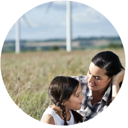 A woman and child together with a field and windmills visible in the distance.