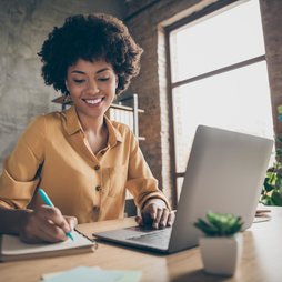 Young woman taking notes during remote meeting