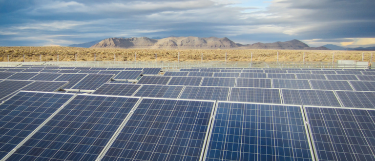 A field of solar panels with mountains in the distance