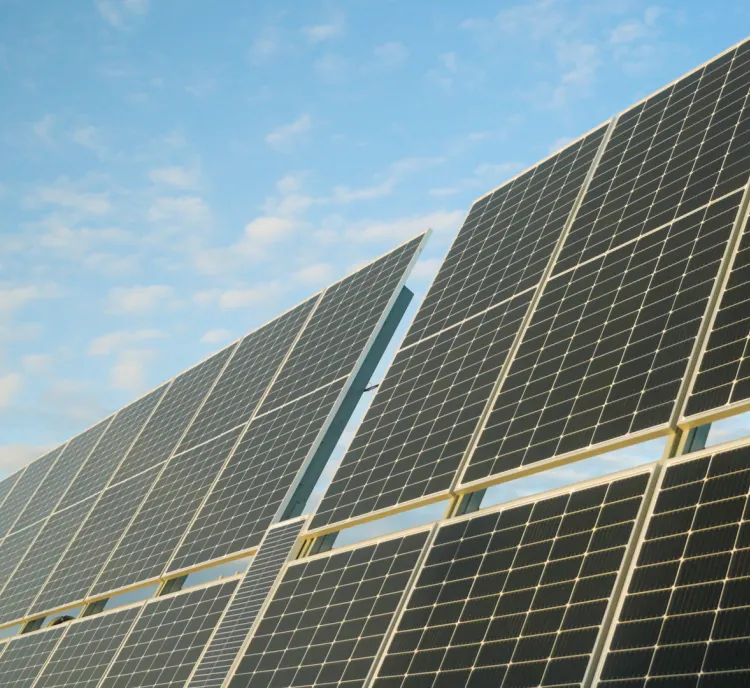 Close-up view of solar panels against a blue sky with scattered clouds.