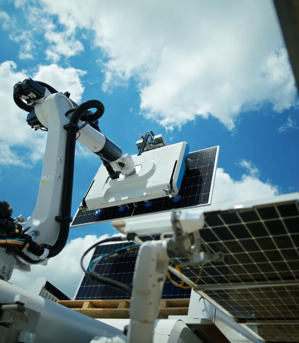 Robotic arm with a solar panel cleaning attachment against a blue sky with clouds.