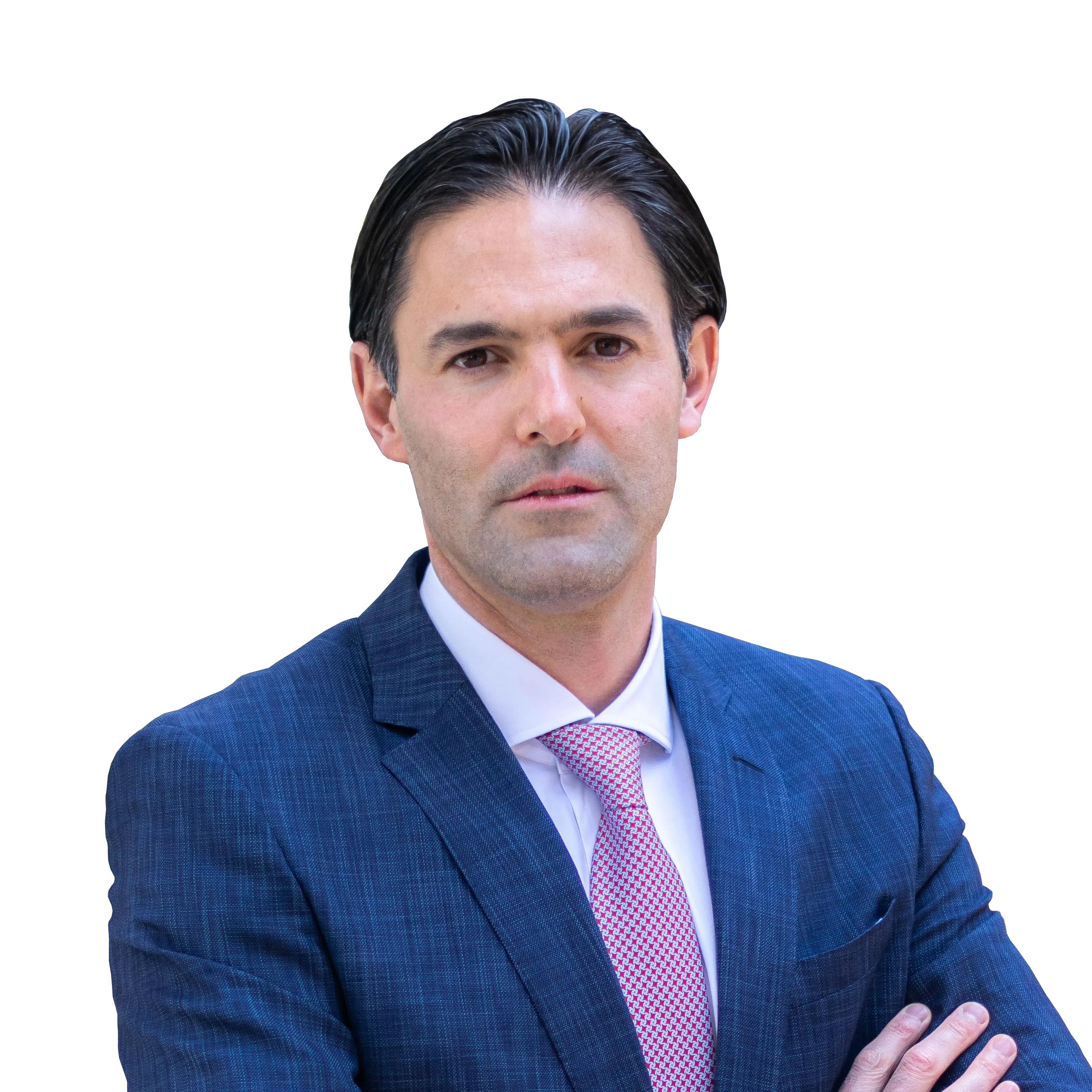 A man in a blue suit with a pink tie stands against a black background, looking directly at the camera.